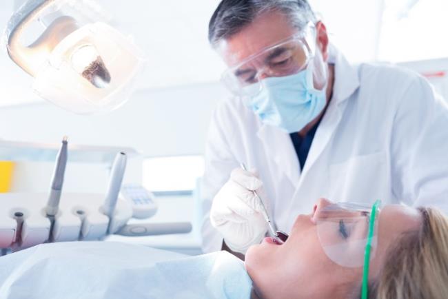 מטופלת עם מסכת מיגון על הפנים אצל בטיפול אצל רופא השיניים